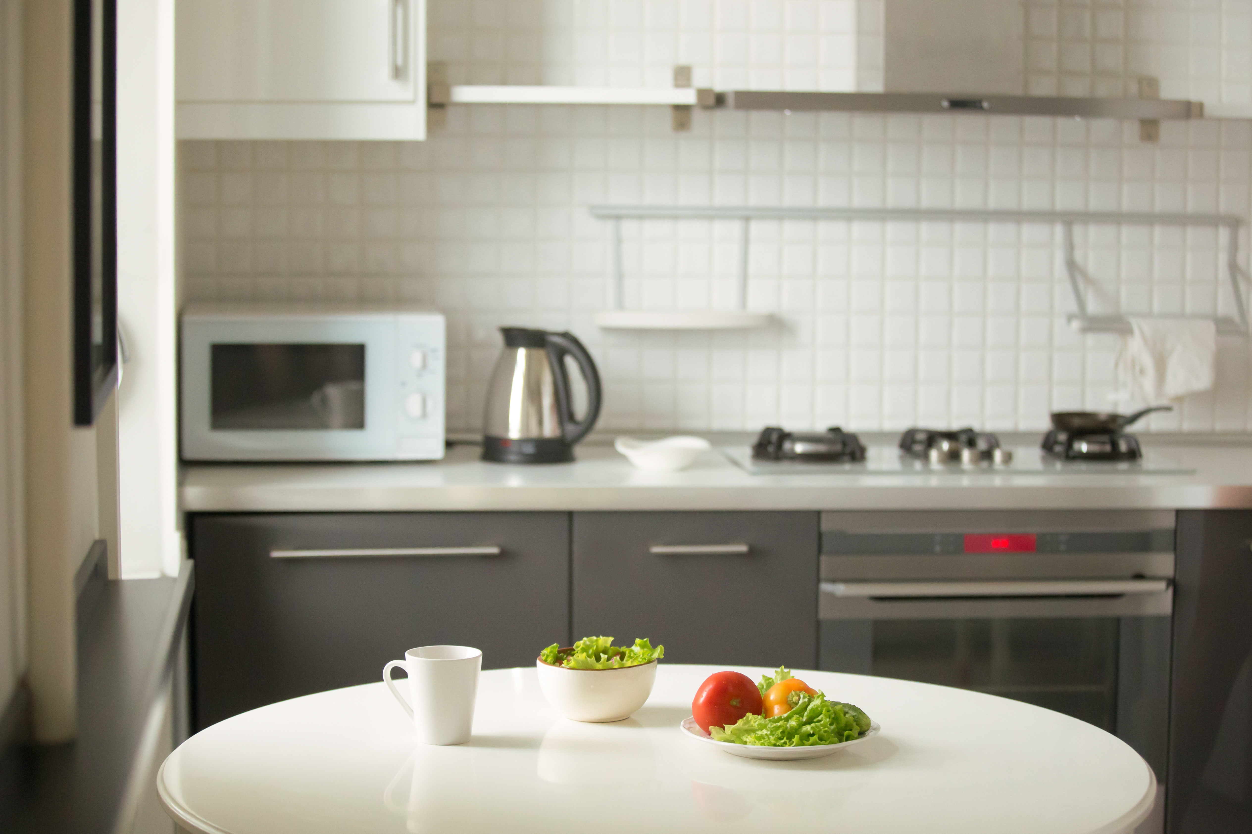 Modern kitchen, a white table, mug and green salad